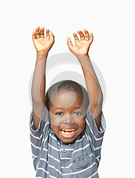 Little African boy holding his hands up in the air whilst laughing and smiling