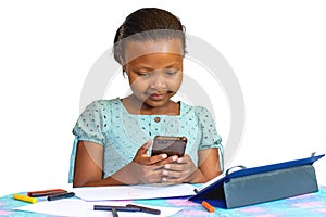 Little african girl doing homework with smartphone and tablet
