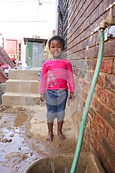 Little African Girl getting splashed by hosepipe water in a Soweto Township back yard