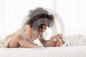 Little african girl kissing and looking at her baby brother with love in bedroom