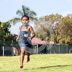 Little african girl running in park.