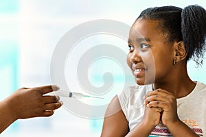 Little african girl scared of syringe with needle.