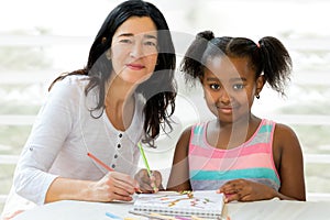 Little african girl and teacher drawing together.