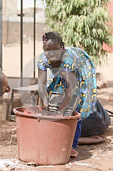 Little African Girl Working at Home Washing Clothes Outdoors