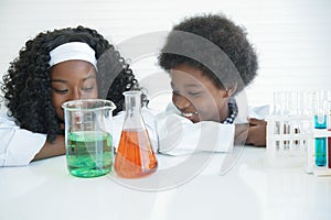 Little African kids learning chemistry and doing a chemical science experiment in a laboratory in school