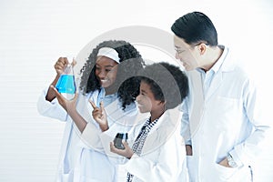 Little African kids studying chemistry and doing chemical science experiment in laboratory at school with Asian teacher man.