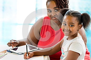 Little african student doing home work with mother.