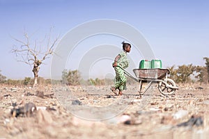 Little African Woman Transporting Fresh Water as a drought symbol photo