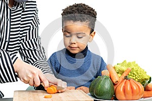 Little afro american boy helping chef preparing vegetable dish