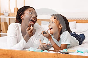 Little afro girl doing makeup with her mom photo