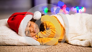 Little afro girl in Santa hat napping on floor