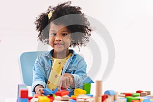 Little afro girl smiling and playing colorful wooden toys