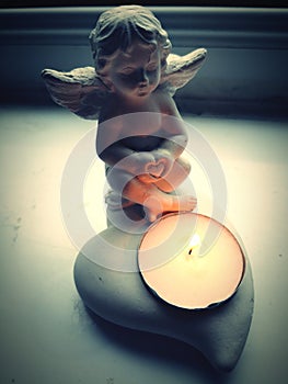 little angel with a heart in her hands , candle holder