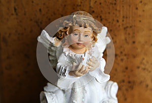 A  little angel holds a pigeonon a wooden background