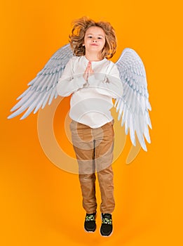 Little angel jump, kids jumping, full body. Valentine's day. Blonde cute child with angel wings on a yellow studio