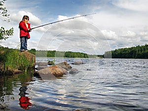 Little angler girl fishing on lake with rod