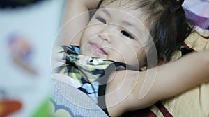 Little Asian baby girl, 2 years old, enjoyed listening to her mother reading aloud a bedtime story from a book