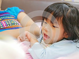 Little Asian baby girl enjoys listening to her mother reading a fairy tale book before her bedtime