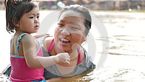 Little Asian baby girl enjoys playing water in a river with her auntie