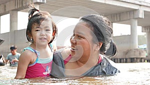 Little Asian baby girl enjoys playing water in a river with her auntie