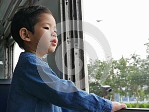 Little Asian baby girl enjoys standing right by a train window and having the wind whips against her face