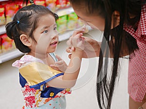 Little Asian baby girl feeding her mother a potato chip - children learn to give