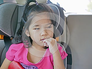 Little Asian baby girl feeling sleepy, sitting in a car seat, during a long trip