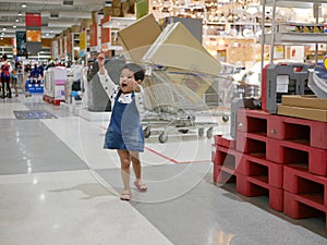 Little Asian baby girl is in a good mood and enjoys walking in a shopping mall