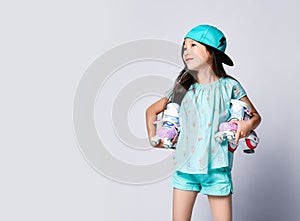 Little asian baby girl kid sitting with roller skates in light blue t-shirt and hat cap happy smiling on white