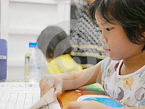 Little Asian baby girl learning to read at home