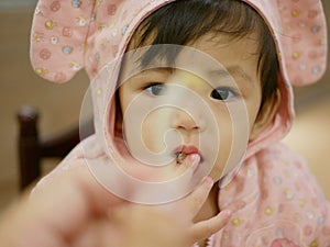 Little Asian baby girl looking at a bean sprout in her mother`s hand