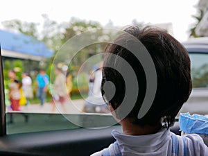 Little Asian baby girl looking at a colorful parade through a car window - baby`s curiosity