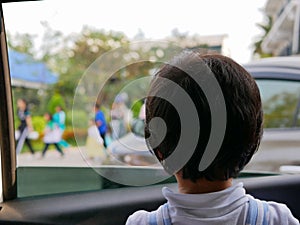 Little Asian baby girl looking at a colorful parade through a car window - baby`s curiosity