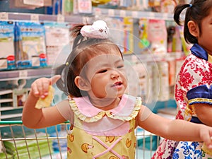 Little asian baby girl enjoy being in a shopping cart waiting for her mother to do shopping