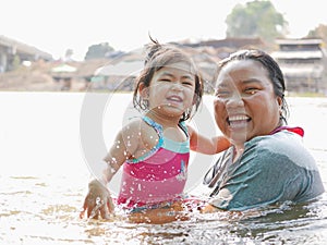 Little Asian baby girl enjoys playing water in a river with her auntie photo