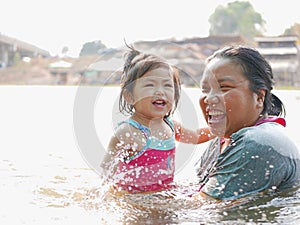 Little Asian baby girl enjoys playing water in a river with her auntie photo