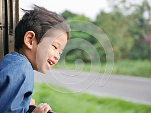Little Asian baby girl enjoys sticking her head out of a train window and having the wind whips against her face photo