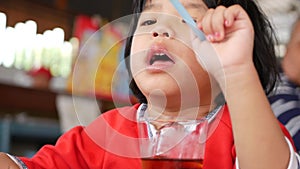 Little Asian baby girl playing a pen while drinking soda pop - baby`s exploration of things around them