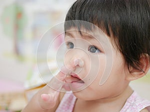 Little Asian baby girl putting her finger into her mouth
