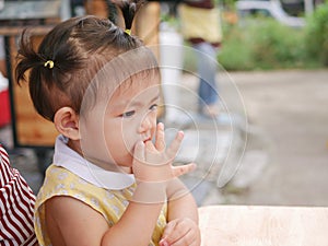 Little Asian baby girl putting her finger into her mouth