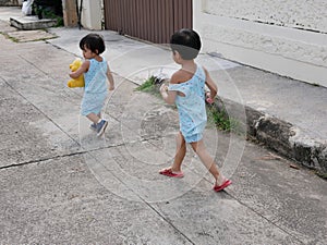 Little Asian baby girl right running after her baby sister and enjoying accompanying her sister while learning and practicin