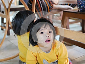 Little Asian baby girlà¸« sitting and playing / exploring with her younger sister under a dinning table at a restaurant