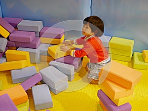 Little Asian baby girl stacking up foam building bricks / blocks at an indoor playground