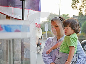 Little Asian baby girl together with her mother watching food vender selling / cooking street food photo