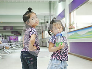 Little Asian baby girls, Thais, sisters, smiling and making cute pose together for indoor photo shoot