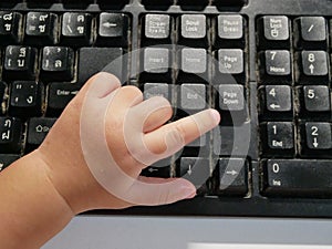 Little Asian baby`s finger pressing on a computer keyboard