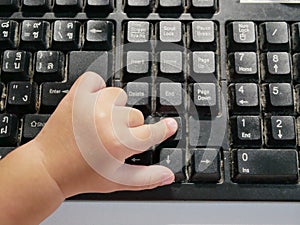 Little Asian baby`s finger pressing on a computer keyboard