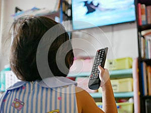 Little Asian baby`s hand holding a television remote control, while watching it at home