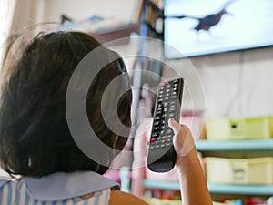 Little Asian baby`s hand holding a television remote control, while watching it at home