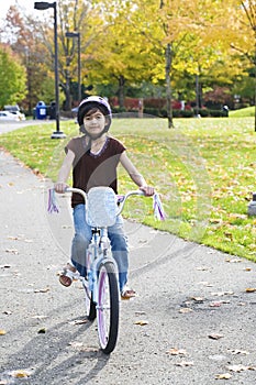 Little Asian biracial girl riding bike in park